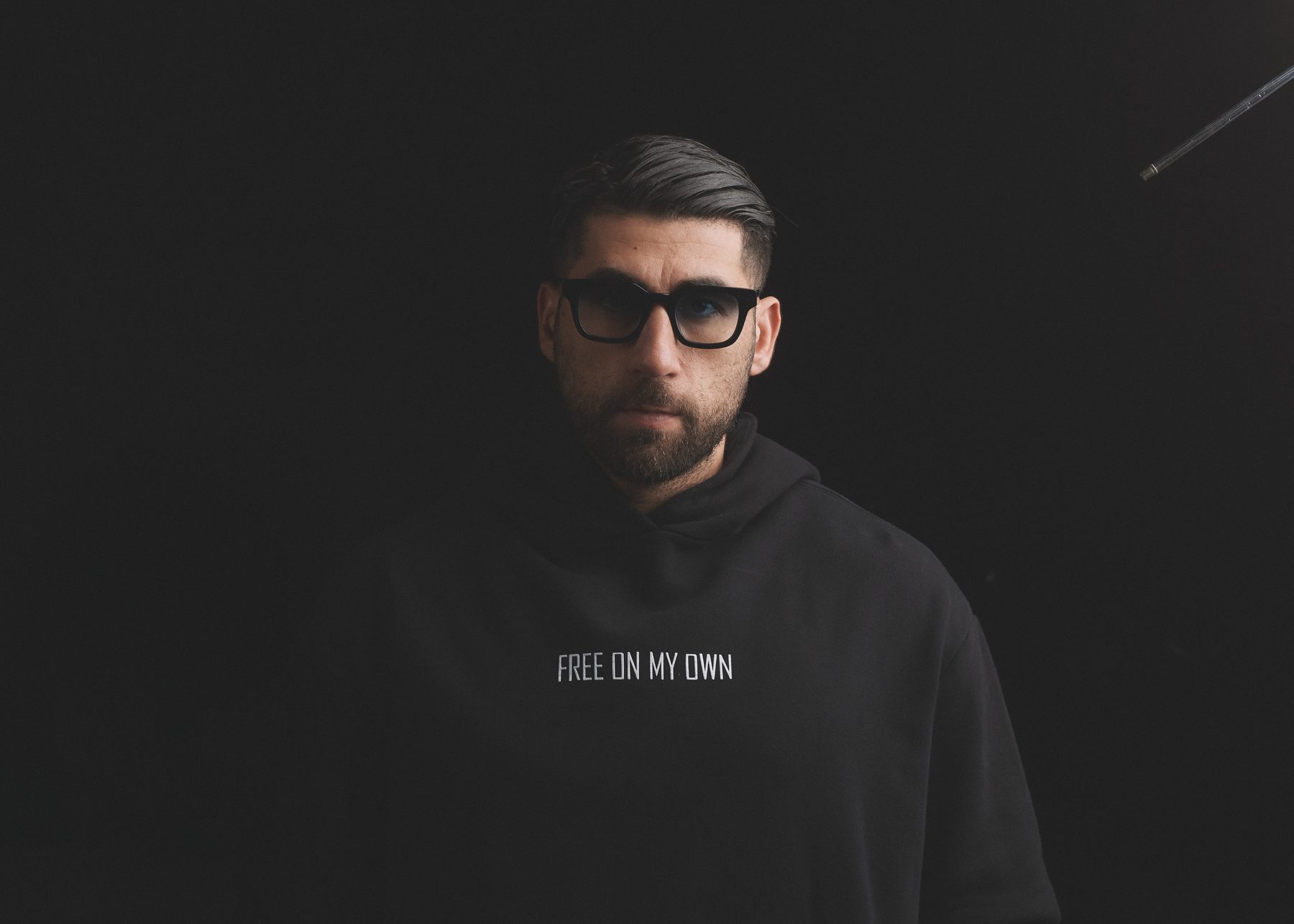 Soberboy, photographed against a black background in a hooded sweatshirt reading Free On My Own